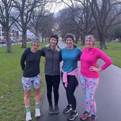 Four smiling women in colourful running outfits stand on a pavement in an urban park - a typical view during a 261 Fearless run