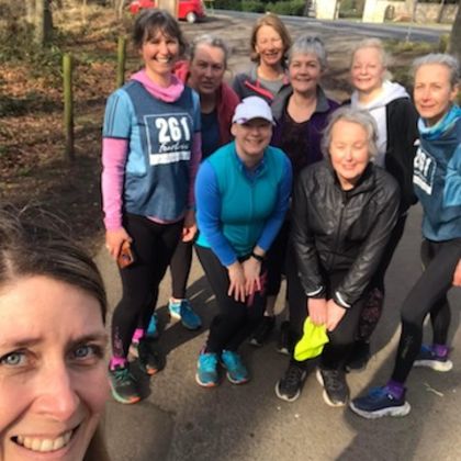 Selfie of a group of women from the 261 Fearless running group on a country road, smiling and waving, in a natural, autumnal setting