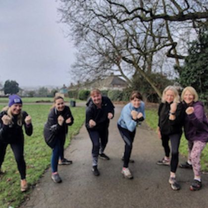 Group of 261 Fearless women posing in a powerful 'battle pose' on a country path, laughing and energised, in a wintry landscape