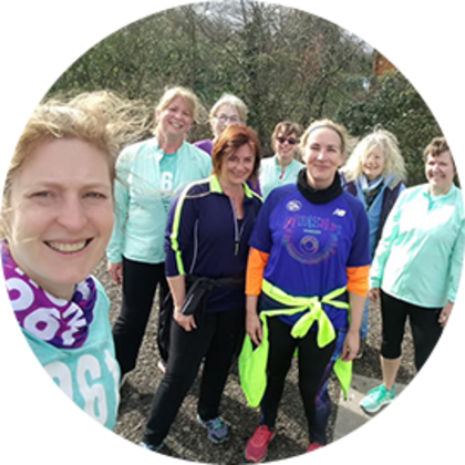 Women of the 261 Fearless running group pose smiling in the park, dressed in brightly coloured running gear
