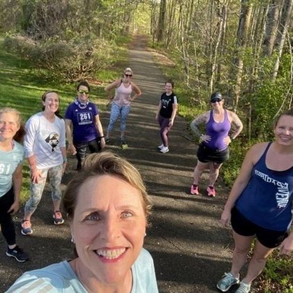 A group of smiling 261 Fearless women take a selfie during a run on a tree-lined path