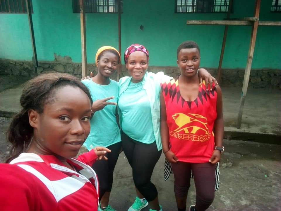 Four joyful 261 Fearless women from Goma take a group selfie, showcasing their camaraderie after a workout session
