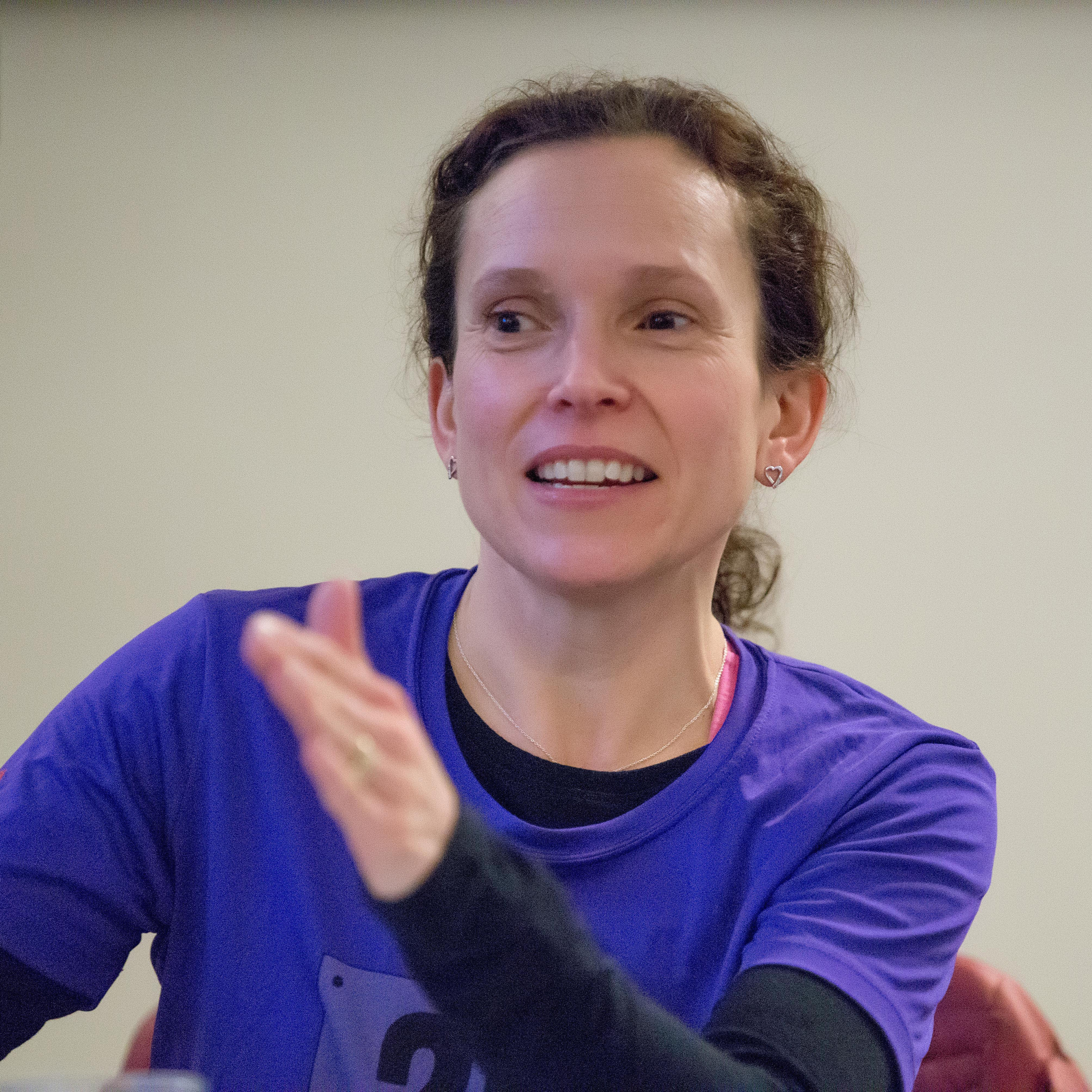 Woman in purple 261 Fearless shirt gestures during a discussion, visibly engaged and passionate, at an indoor meeting