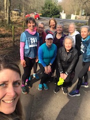 Group photo of women from the 261 Fearless women's running group on a country road, dressed in casual running clothes, posing together for a photo, promoting a sense of community and joy
