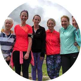 Group of women, dressed in colourful sportswear, posing joyfully outdoors, demonstrating the team spirit and enthusiasm of the 261 Fearless running group