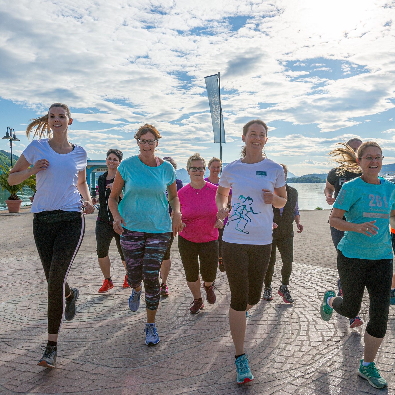 A group of smiling women in running gear enjoy a run together along a promenade with a river in the background - an image that reflects the sense of community and positive atmosphere at the 261 Fearless running club